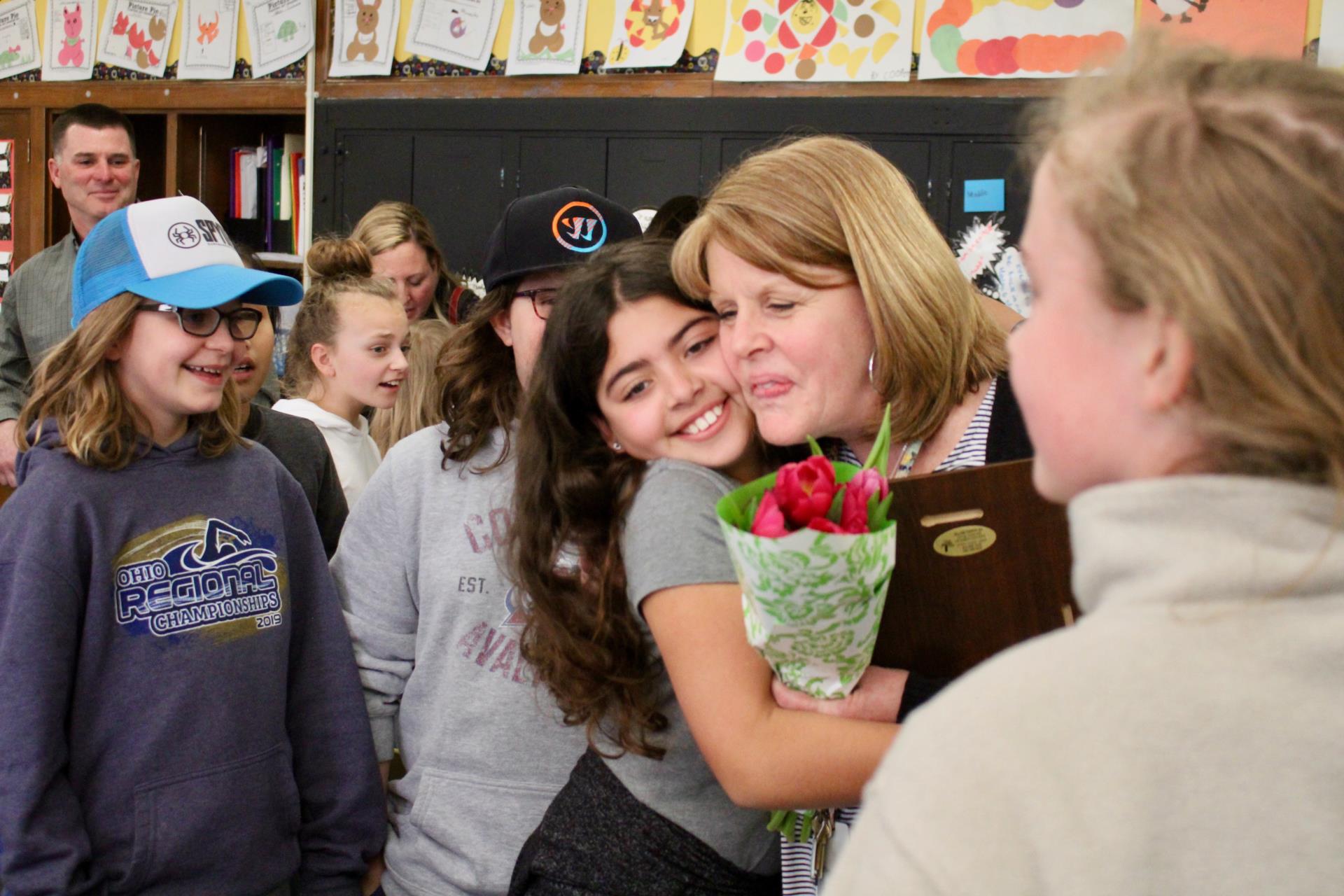 A student hugging Molly Hinkle while others look on
